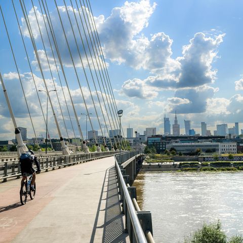 Ein Radfahrer fährt bei Sonnenschein über eine Brücke in Warschau
