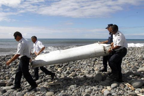 Techniker tragen ein Wrackteil über einen Strand bei Saint-Andre de la Reunion, das vom Flugzeugabsturz von MH370 stammt.