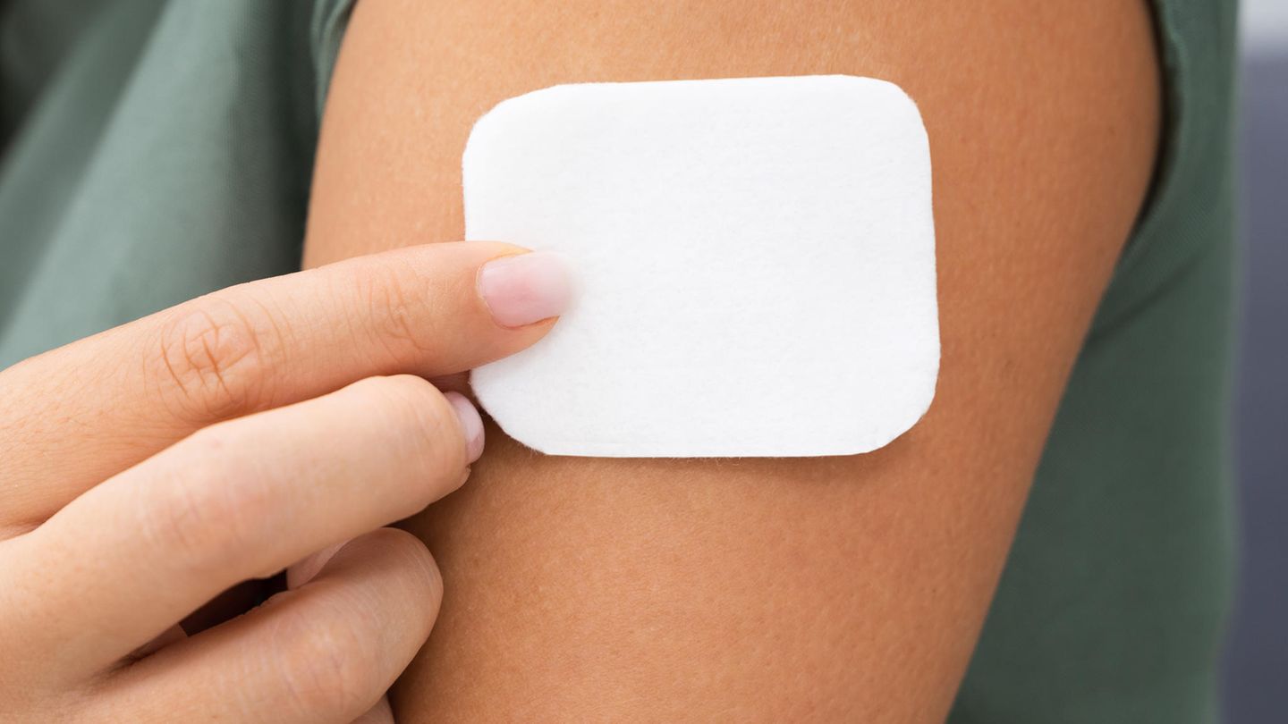 Hormonersatztherapie: Eine Frau klebt sich ein Pflaster auf den Oberarm Hormonersatztherapie: Eine Frau klebt sich ein Pflaster auf den Oberarm