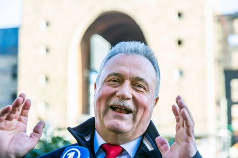 Claus Weselsky hebt bei einer Pressekonferenz lächelnd beide Hände