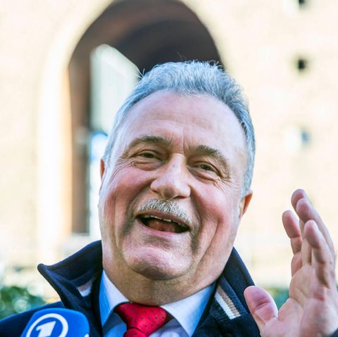 Claus Weselsky hebt bei einer Pressekonferenz lächelnd beide Hände