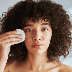 Abschminken: Eine Frau hält ein Wattepad an ihr Gesicht.