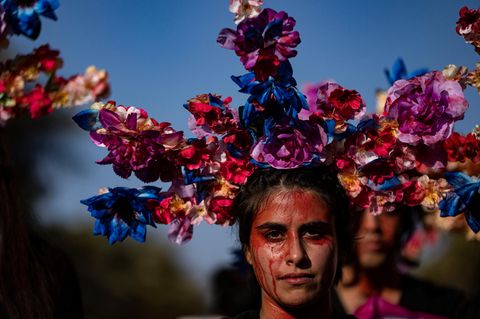 Eine Frau mit roter Farbe in Gesicht und ausladender Blumenkrone am Weltfrauentag