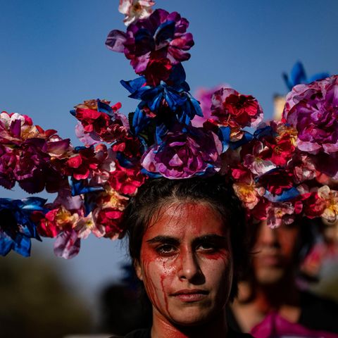 Eine Frau mit roter Farbe in Gesicht und ausladender Blumenkrone am Weltfrauentag