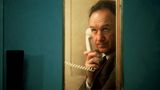 Gene Hackman in einer Telefonkabine mit einem weißen Telefon in der Hand.