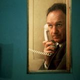 Gene Hackman in einer Telefonkabine mit einem weißen Telefon in der Hand.