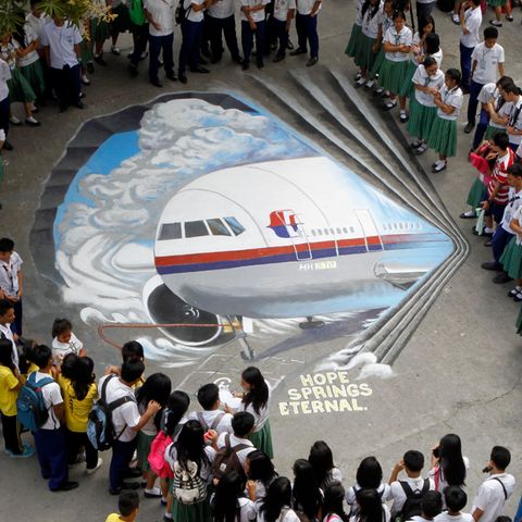 Schüler versammeln sich um ein dreidimensionales Kunstwerk, das den verschollenen Flug MH370 der Malaysia Airlines zeigt