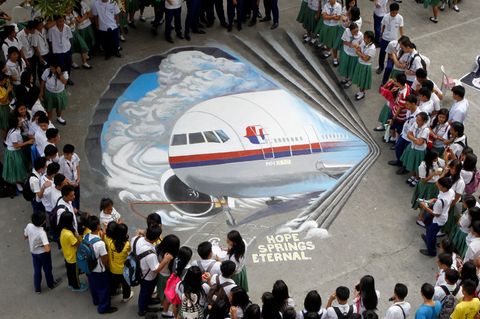 Schüler versammeln sich um ein dreidimensionales Kunstwerk, das den verschollenen Flug MH370 der Malaysia Airlines zeigt