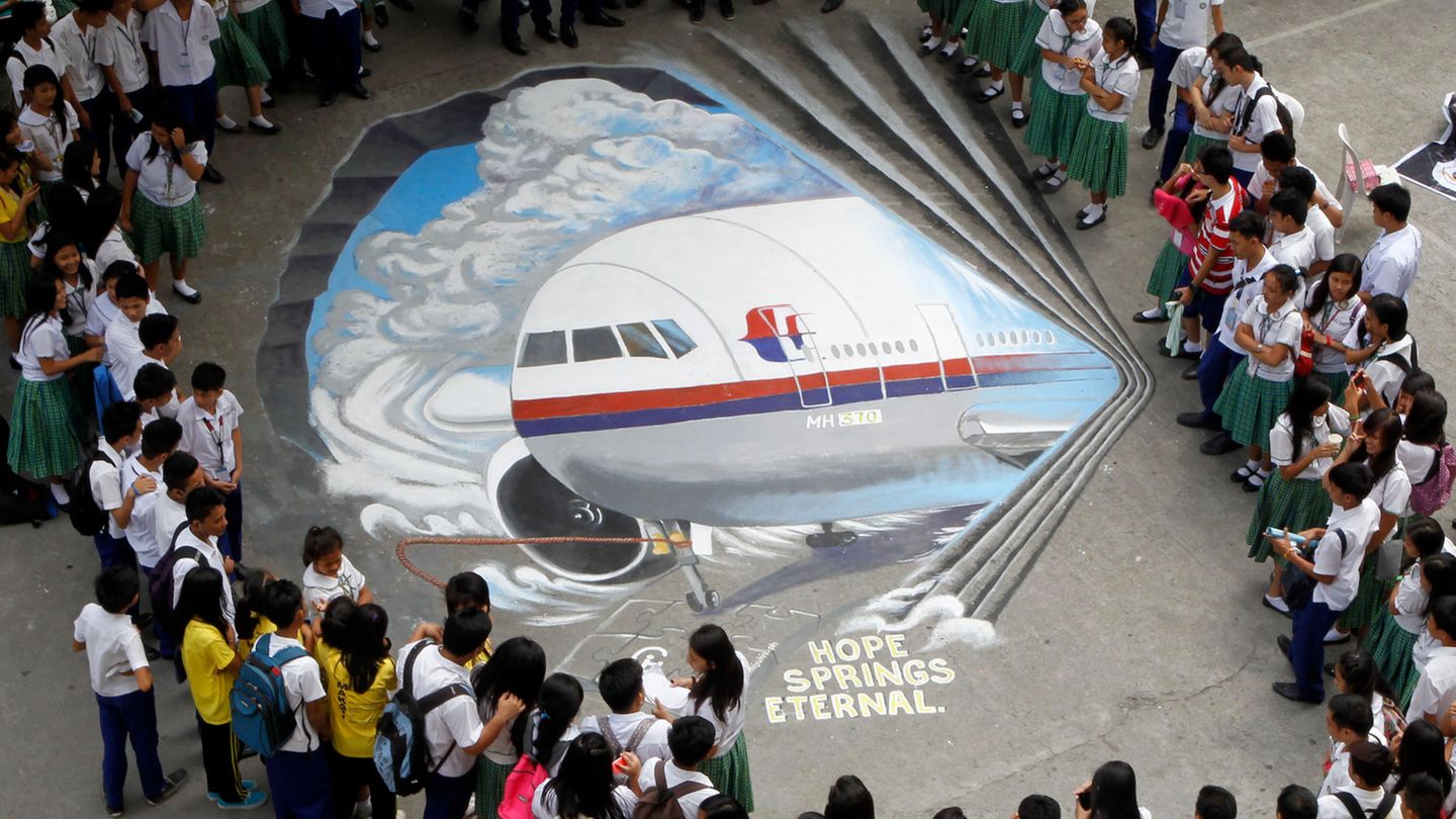 Schüler versammeln sich um ein dreidimensionales Kunstwerk, das den verschollenen Flug MH370 der Malaysia Airlines zeigt