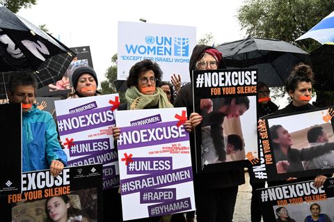 Frauen mit zugeklebten Mündern halten Transparente hoch, um sich mit den Opfern sexualisierter Gewalt zu solidarisieren