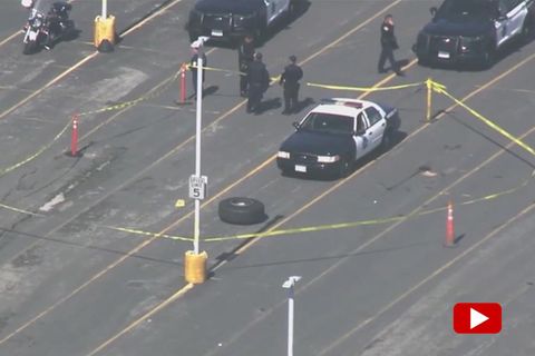 Ein abgefallenes Flugzeug-Rad liegt auf einem Parkplatz vor einem Polizeiauto