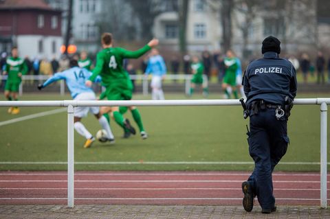 Ein Polizist beobachtet ein Fußballspiel von Amateuren