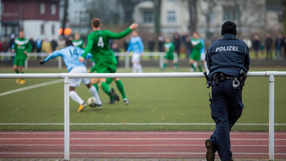 Ein Polizist schaut sich ein Amateur-Fußballspiel an