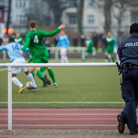 Ein Polizist beobachtet ein Fußballspiel von Amateuren