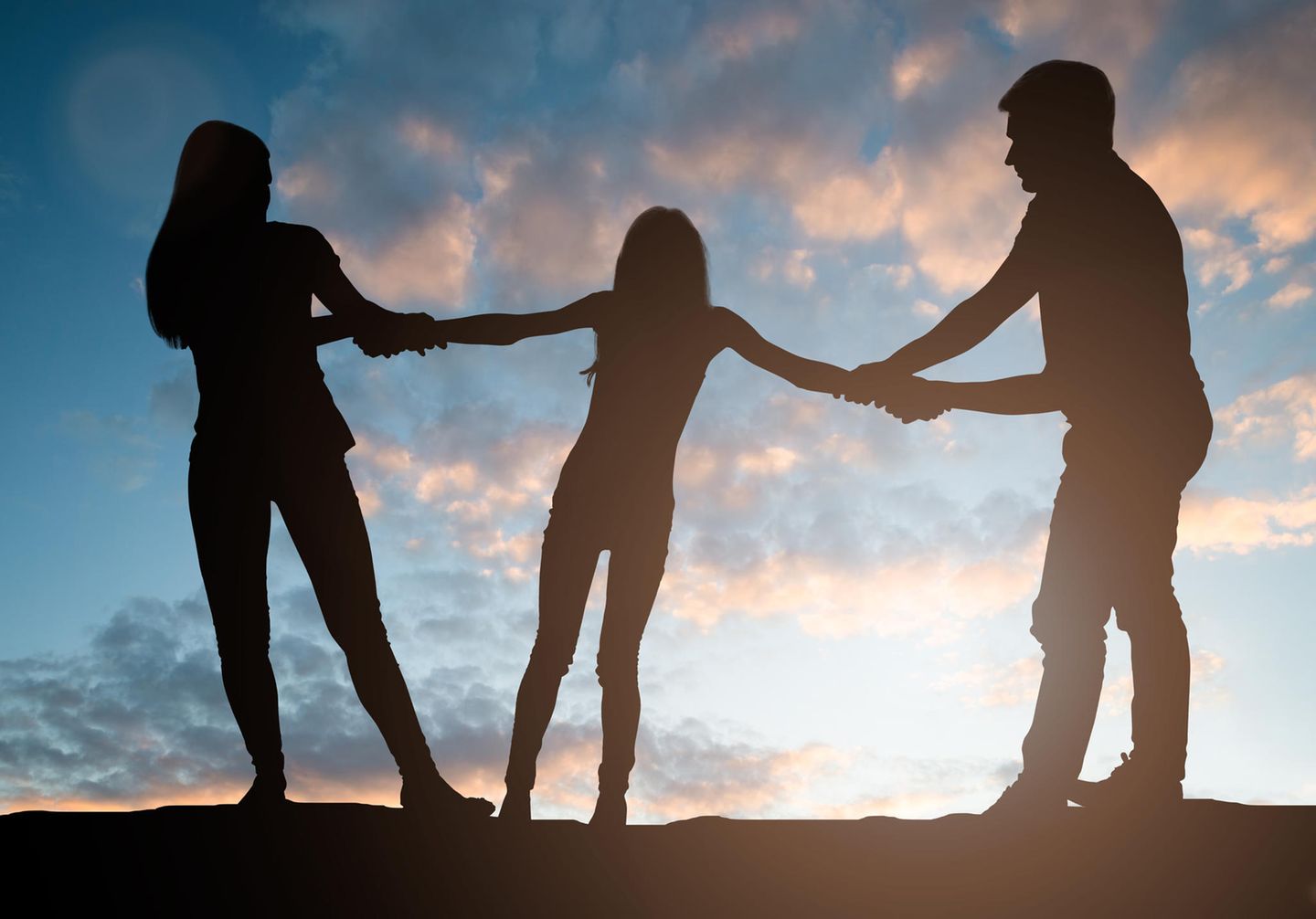 Silhouette von zwei Erwachsenen, die an einem Kind zerren