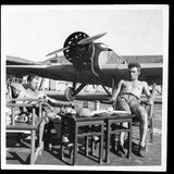 Pilot und Funkermaschinist sitzen mit freiem Oberkörper vor ihrer Maschine