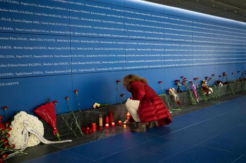 Eine Frau zündet eine Kerze an der Gedenktafel für die Opfer des islamistischen Bombenterrors im Atocha Bahnhof in Madrid an