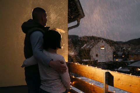 Zwei Personen von hinten Arm in Arm auf einem Balkon