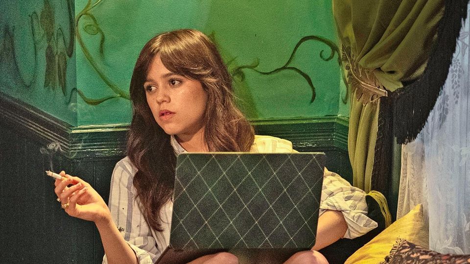 Jenna Ortega sitzt rauchend vor ihrem Laptop