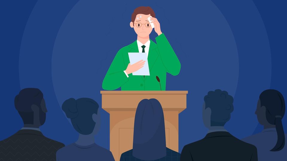 Ein schwitzender Mann steht an einem Podium vor Publikum