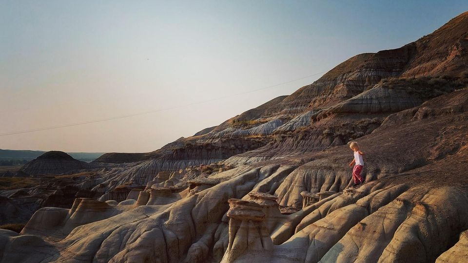 Ein Kleinkind klettert über eine Sandsteinlandschaft in den Badlands