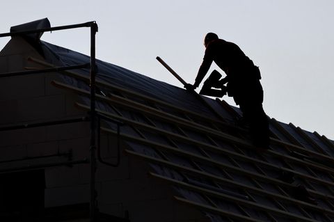 Ein Dachdecker arbeitet auf dem Dach eines Einfamilienhauses