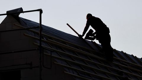 Ein Dachdecker arbeitet auf dem Dach eines Einfamilienhauses