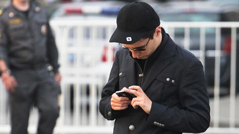 Telegram-Gründer Pawel Durow mit Cap und Sonnenbrille schaut auf sein Handy