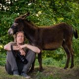 Der Fotograf Gordon Welters sitzt vor einem Esel auf dem Boden