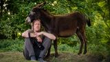 Der Fotograf Gordon Welters sitzt vor einem Esel auf dem Boden