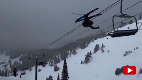 Ein Skifahrer fliegt durch die Luft und bleibt an einem Sessellift hängen