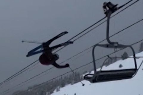 Ein Skifahrer fliegt durch die Luft und bleibt an einem Sessellift hängen