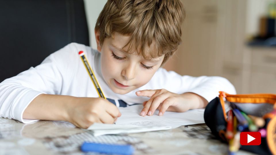 Ein Junge sitzt am Tisch an seinen Mathe-Aufgaben.
