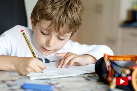 Ein Junge sitzt am Tisch an seinen Mathe-Aufgaben.
