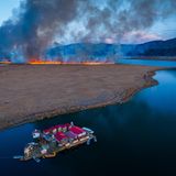 Ein schwimmendes Dorf im Titicacasee und ein herannahender Waldbrand im Hintergrund