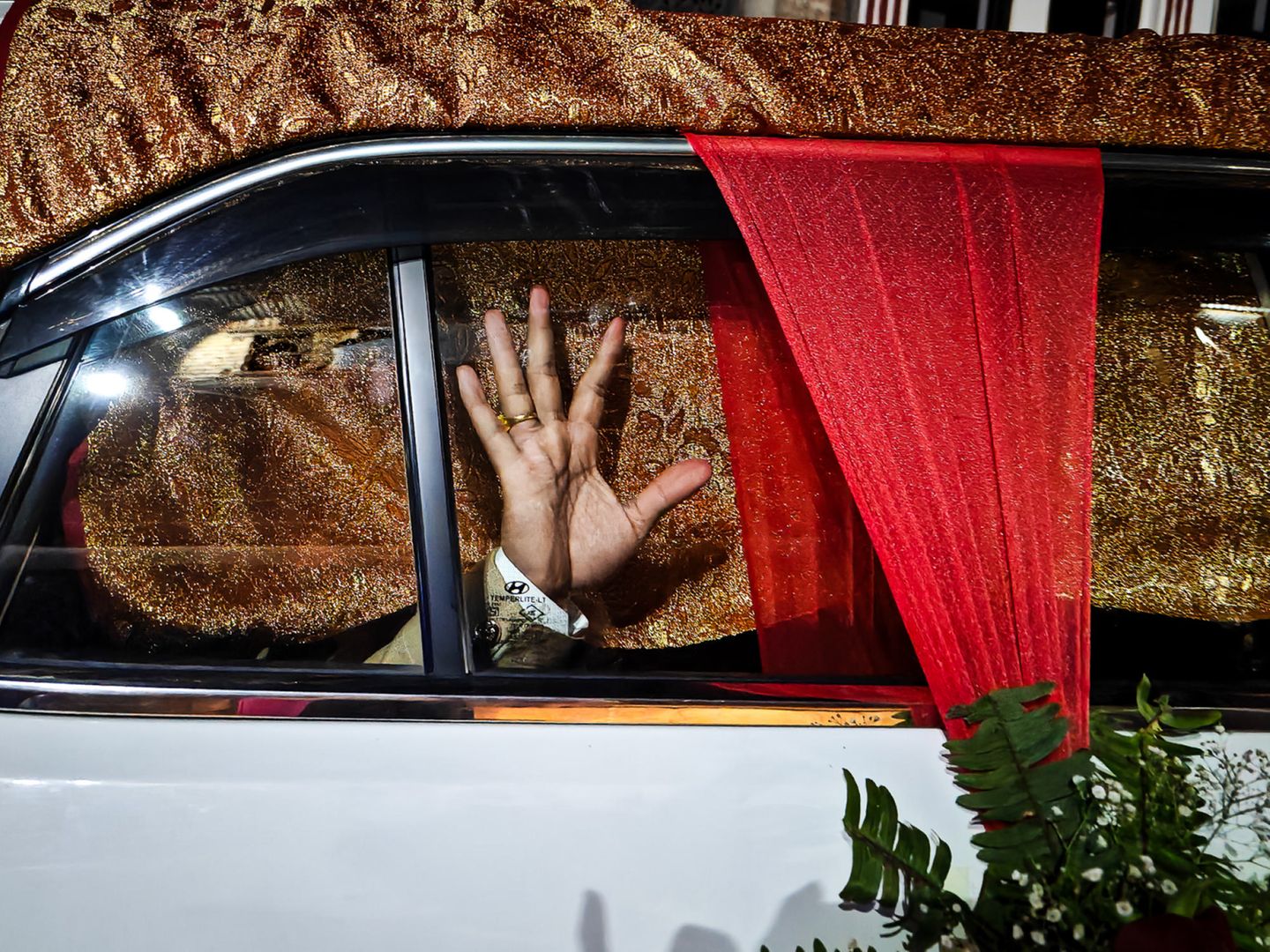 Eine Hand eines Mannes ist gegen die Scheibe einer geschmückten Limousine gedrückt
