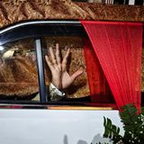 Eine Hand eines Mannes ist gegen die Scheibe einer geschmückten Limousine gedrückt