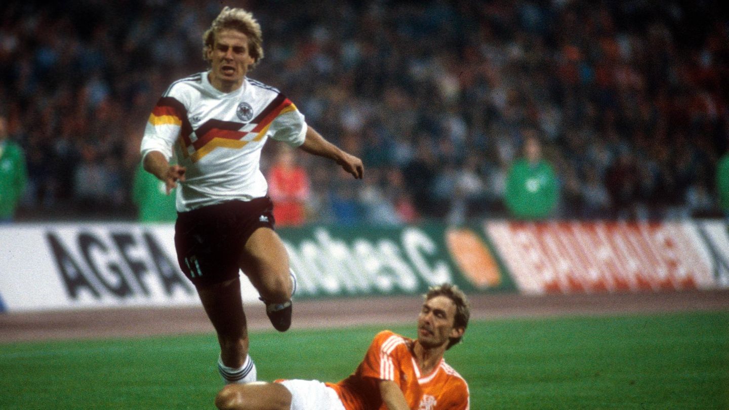 Kaum kamen die ersten Farbtupfer aufs deutsche Trikot, gab es kein Halten mehr: Bei der EM 1988 wurde aus den dezenten schwarz-rot-goldenen Ringen an Kragen und Ärmeln ein alles dominierendes Brustelement. Im Vergleich zu den schlichten Versionen der Vergangenheit wirkte das Shirt wie eine Discokugel. Für Verwirrung sorgte es aber höchstens bei den Fans. Im Halbfinale konnten sich die Niederlande gegen Jürgen Klinsmann und Co. in den bunten Leibchen durchsetzen. 