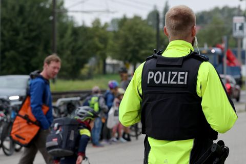 Ein Polizist beobachtet Kinder und Jugendliche vor einer Schule in Mecklenburg-Vorpommern