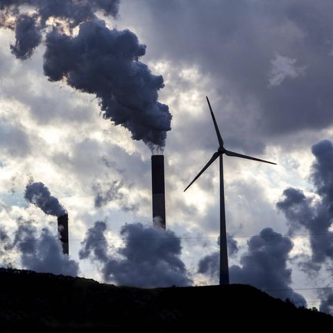Windenergieanlagen neben rauchenden Schornsteinen