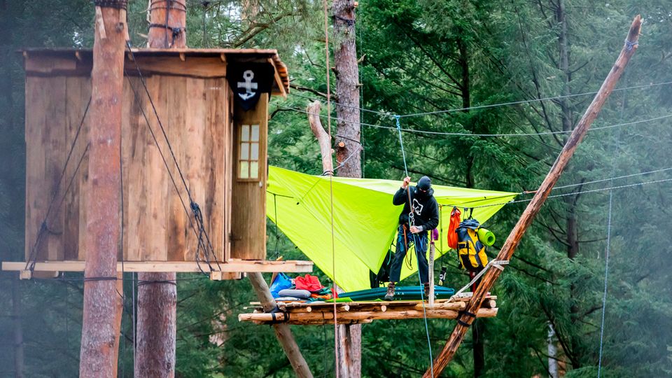 Ein Aktivist seilt sich im Camp der Initiative "Tesla stoppen" in dem Kiefernwald nahe der Tesla-Gigafactory ab Ein Aktivist seilt sich im Camp der Initiative "Tesla stoppen" in dem Kiefernwald nahe der Tesla-Gigafactory ab