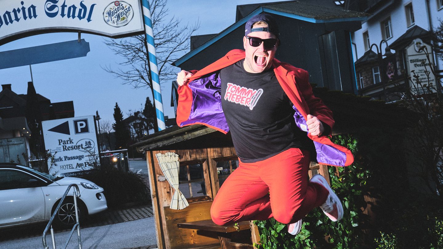 Ein Mann im roten Anzug, Sonnenbrille und Mütze springt in die Luft