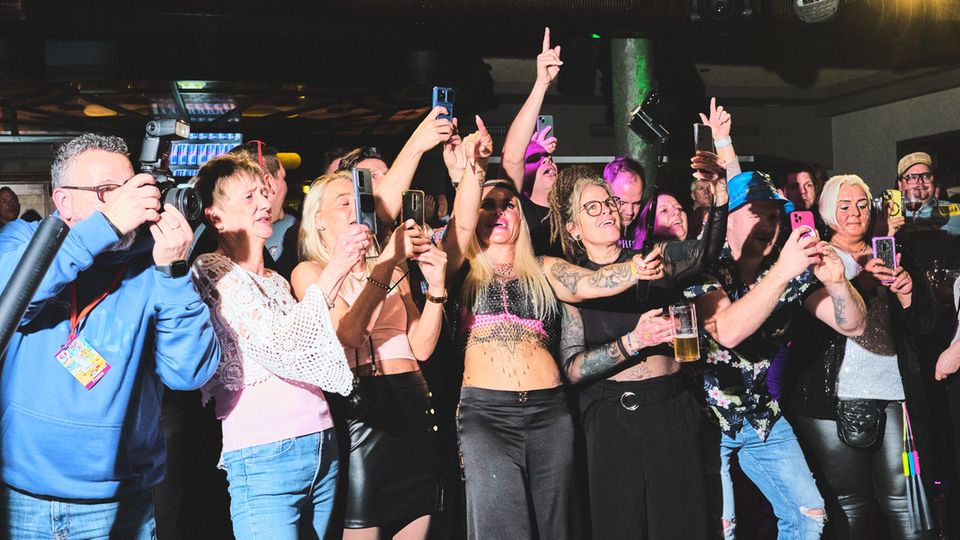 Frontalansicht auf ein fröhliches Publikum, viele mit smartphones in der Hand