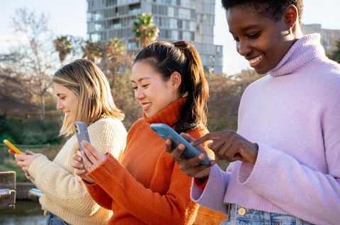Drei Frauen nutzen ihr unbegrenztes Datenvolumen mit ihren Smartphones im Park.