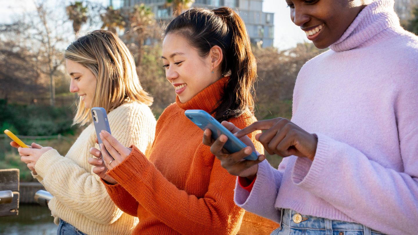 Drei Frauen nutzen ihr unbegrenztes Datenvolumen mit ihren Smartphones im Park.