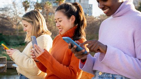 Drei Frauen nutzen ihr unbegrenztes Datenvolumen mit ihren Smartphones im Park.