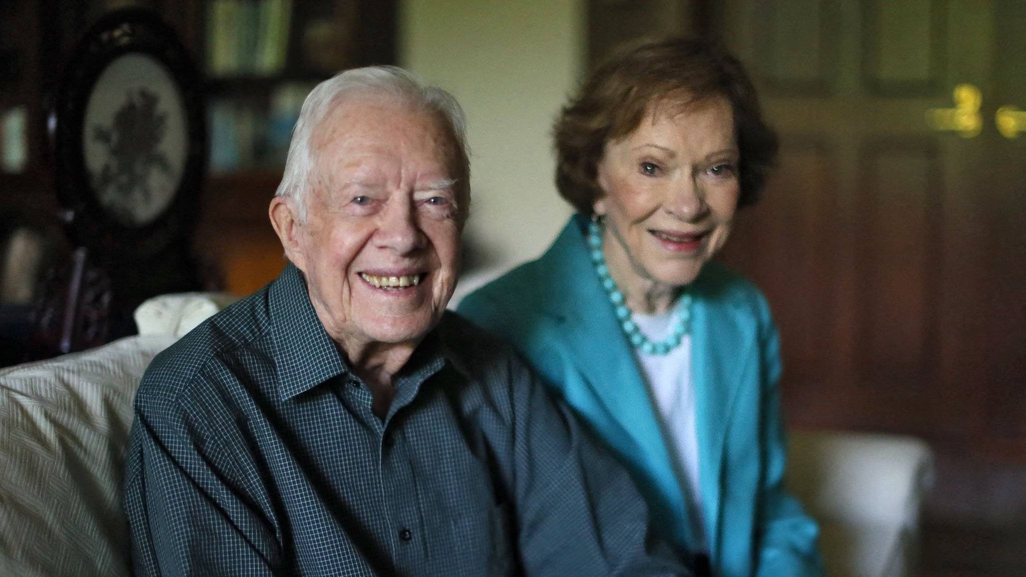 Jimmy und Rosalynn Carter sitzen auf einem Sofa und lächeln in die Kamera