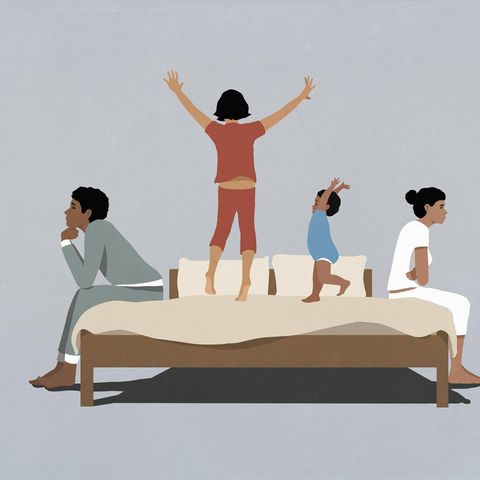 Kinder turnen zwischen ihren Eltern auf einem Bett