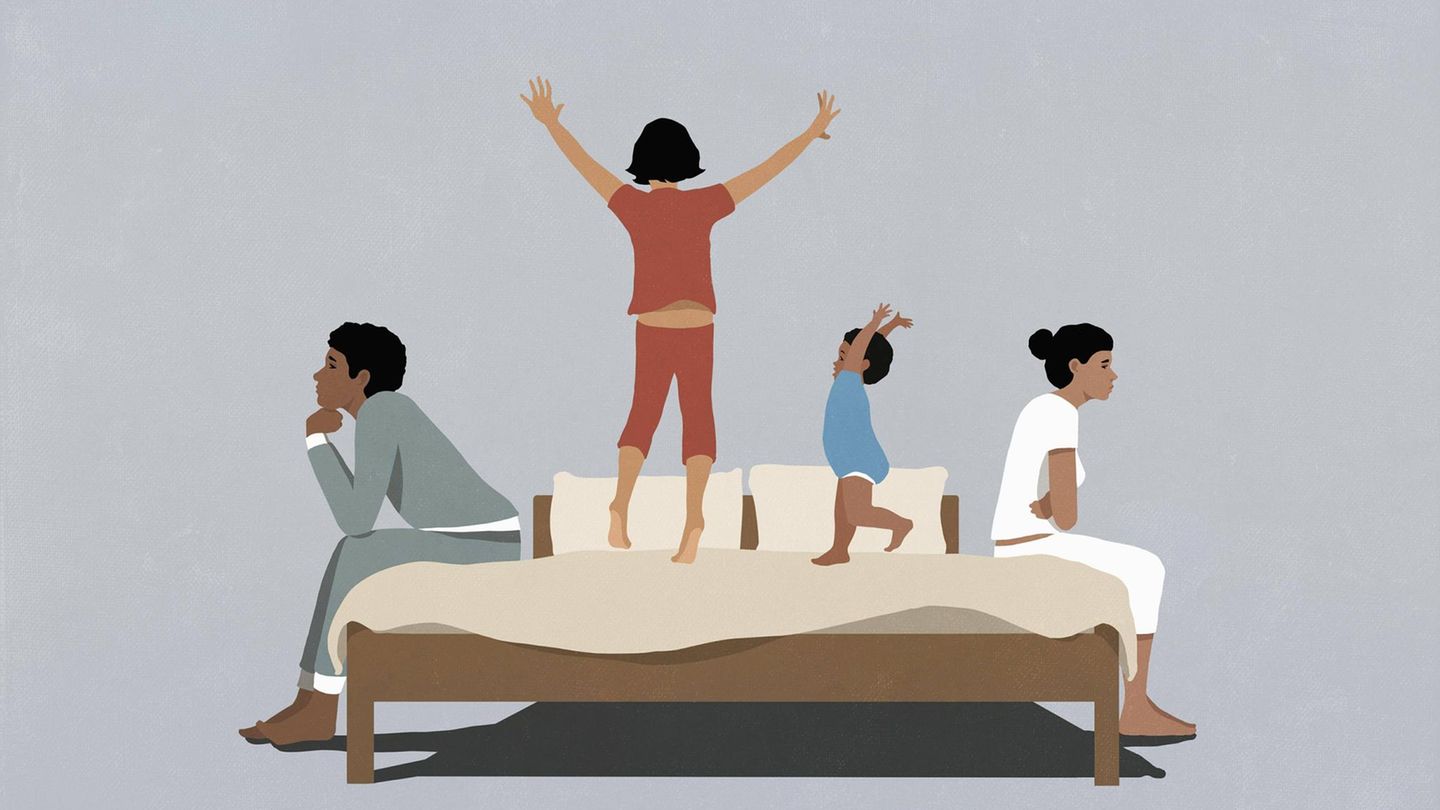 Kinder turnen zwischen ihren Eltern auf einem Bett