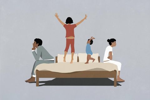 Kinder turnen zwischen ihren Eltern auf einem Bett
